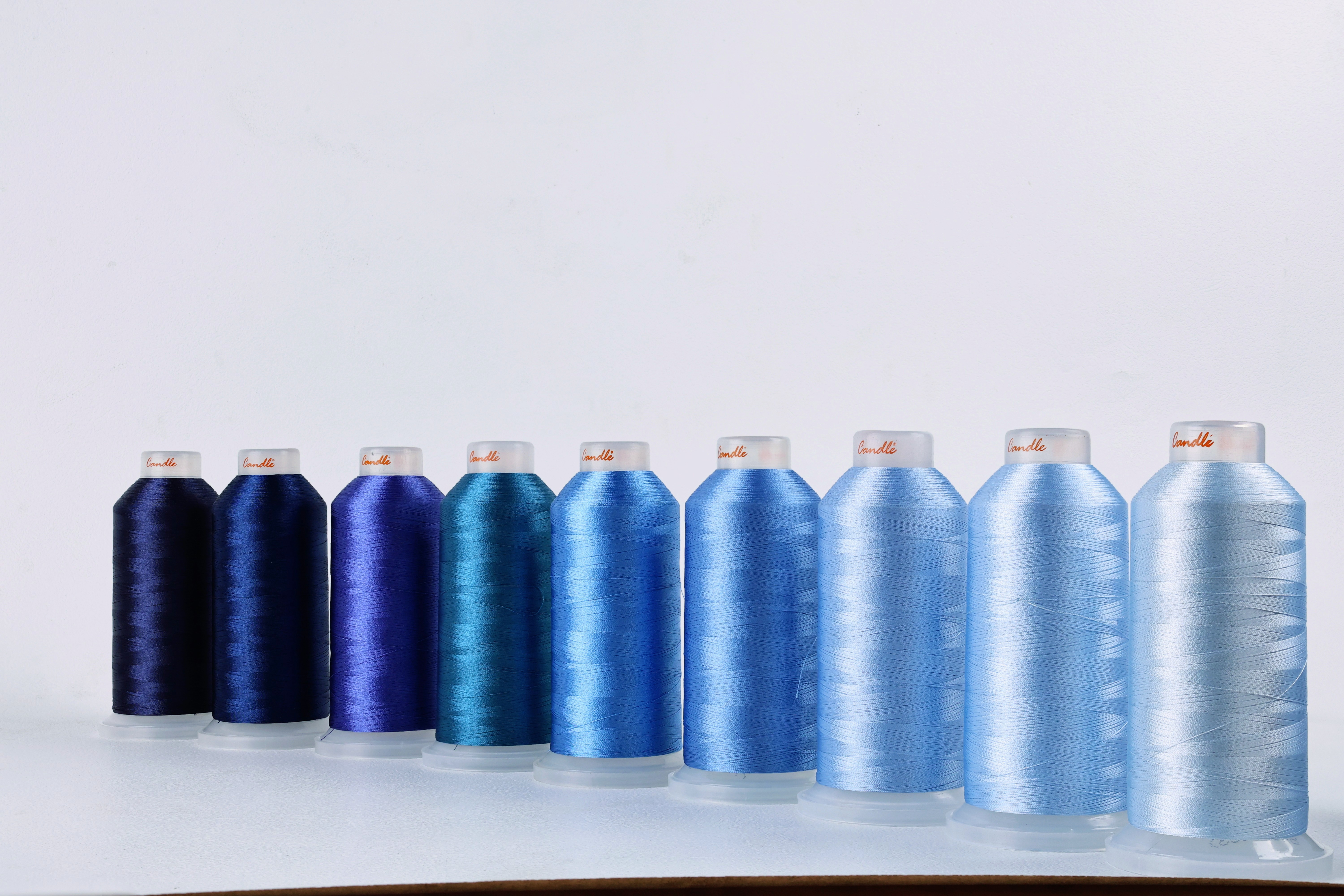 Colorful industrial thread cones arranged in a row with blue tones